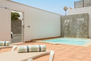 - une piscine avec 2 chaises et une fontaine dans l'établissement Villa con piscina junto a la playa, à La Estrella