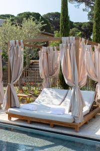a bed in a canopy next to a pool at Hôtel L'Escalet in Ramatuelle
