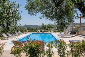 einen großen Pool mit Stühlen und Bäumen in der Unterkunft Villa Luna, 5 bedrooms, Private Pool, Hot Tub, Garden in Skalánion