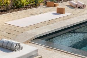 a swimming pool with a table and a glass of wine at Hôtel L'Escalet in Ramatuelle