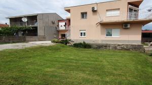 a large house with a green lawn in front of it at Studio apartman Antonio in Metković