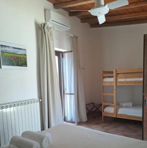 a bedroom with a bed with a ceiling fan and a window at Fattoria Manostalla Villa Chiarelli in Balestrate