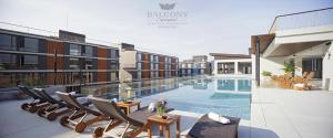 a swimming pool with chairs next to a building at Balcony Courtyard Sriracha Hotel & Serviced Apartments in Si Racha