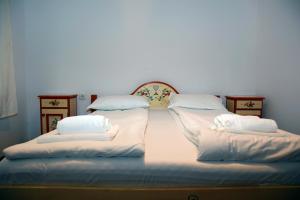 Pensiunea 7 Tei في سيسناديورا: سرير كبير عليه أغطية ووسائد بيضاء
