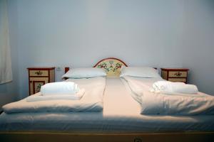a large bed with white sheets and pillows on it at Pensiunea 7 Tei in Cisnadioara