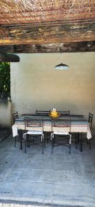 einen Tisch und Stühle unter einem Holzdach in der Unterkunft Maison provençale en pierres sèches in Gordes