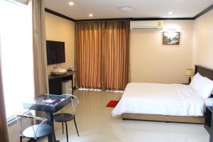 Triton Hotel Nakhonratchasima โรงแรมไททัน في ناخون راتشاسيما: غرفة نوم بسرير وطاولة ومكتب