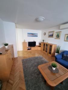 ein Wohnzimmer mit einem blauen Sofa und einem Tisch in der Unterkunft Drago Apartman in Šibenik