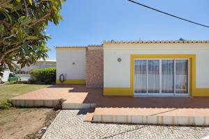 una casa con una puerta amarilla delante de ella en Casa Do Poço, en Budens