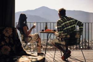 Ein Mann und eine Frau sitzen an einem Tisch mit Weingläsern. in der Unterkunft Nikolaus by AvenidA Panoramic Wellness Suites in Zell am See