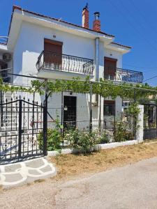 a white house with a balcony and a fence at SUNDAY HOUSE in Skala Kallirakhis