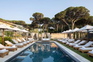 a swimming pool with lounge chairs and umbrellas at Hôtel L'Escalet in Ramatuelle