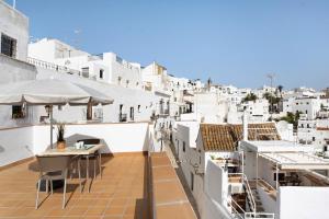 einen Balkon mit Tischen, Sonnenschirmen und weißen Gebäuden in der Unterkunft Apartamento La Fuente in Vejer de la Frontera