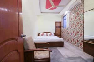 a small room with a bed and a ceiling fan at Hotel O Home Cozy Studio Collage Square Hotel Maya International Near St. Thomas's Church in Kolkata