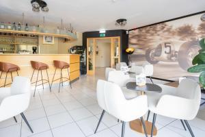 a restaurant with white chairs and a counter at Hotel-Restaurant Stand'Inn in Foetz