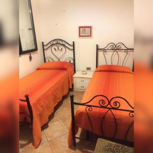 2 camas en una habitación con sábanas de color naranja en Villa Vasagè, en Torre Squillace