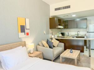 a room with a bed and a couch and a kitchen at Cosmos Living Spacious Studio With Balcony in Dubai