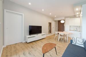 a living room with a tv and a table with chairs at YOURAPART Sienna Grobla Free Parking in Gdańsk