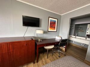 Habitación de hotel con escritorio y TV en la pared en Studio Suites, en San Antonio