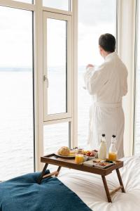 un hombre con una bata de pie en una habitación mirando por la ventana en Jegtvolden Fjordhotell, en Straumen