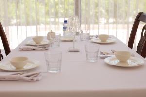 una mesa blanca con platos y vasos. en Tashkent Hotel, en Nukus