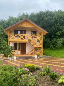 uma grande casa de madeira com um alpendre num quintal em Карпатська Модрина em Kosiv