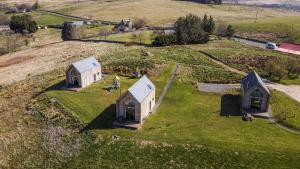 an aerial view of two small houses on a grassy hill at Tarset Tor - Bothy 3 in Greenhaugh