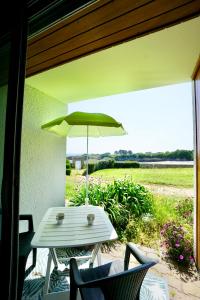 einen Tisch und Stühle mit Sonnenschirm auf einer Terrasse in der Unterkunft La Lézardière *Front de mer* in Ploemeur