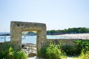 einen Bogen in einer Steinmauer neben einem Strand in der Unterkunft La Lézardière *Front de mer* in Ploemeur