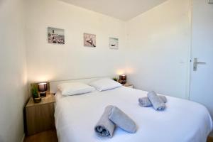 ein Schlafzimmer mit einem weißen Bett und Handtüchern darauf in der Unterkunft La Lézardière *Front de mer* in Ploemeur