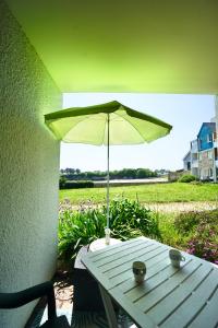 einen Tisch mit einem grünen Sonnenschirm auf einer Terrasse in der Unterkunft La Lézardière *Front de mer* in Ploemeur