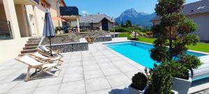 a patio with a swimming pool and two chairs and an umbrella at Chambre vue lac av piscine in Prunières +5 photos