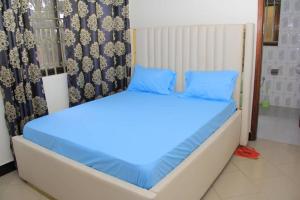 uma cama com almofadas azuis num quarto em Da Rose Guest House and SPA em Kampala