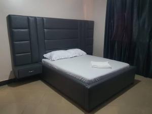 uma cama num quarto com uma cabeceira preta em Da Rose Guest House and SPA em Kampala