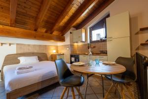 Inn Aosta Apartments في أَويستا: غرفة نوم بسرير وطاولة وكراسي