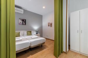 1 dormitorio con 1 cama con cortinas verdes en BNBHolder Apartamentos en Sol Confort 4, en Madrid