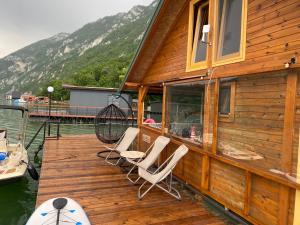 een houten terras met stoelen en een huis aan het water bij Viridian Three Boathouse Micah, PERUCAC LAKE in Perućac