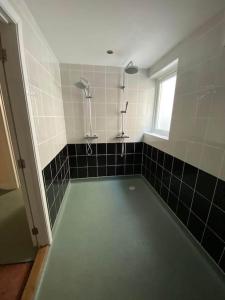 a bathroom with a shower and black and white tiles at Karrek View - Trebarwith Strand (Sleeps 8-10) in Treknow