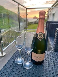 a bottle of champagne and two wine glasses on a table at Karrek View - Trebarwith Strand (Sleeps 8-10) in Treknow