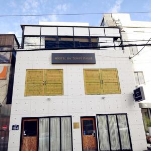 un bâtiment blanc avec des portes brunes et un panneau sur celui-ci dans l'établissement All Stay Inn Seoul, à Séoul