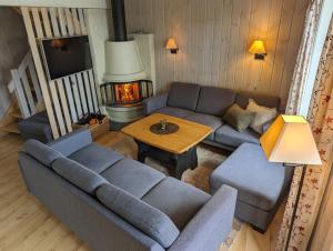 uma sala de estar com um sofá, uma mesa e uma lareira em Grønolen Fjellgard em Beitostøl