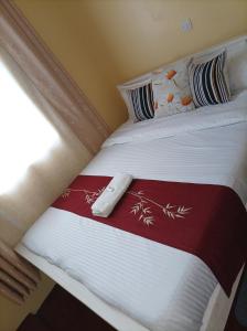 Una cama con una manta roja y blanca y una ventana en Devine 1 bedroom on Moi Southlake road en Naivasha