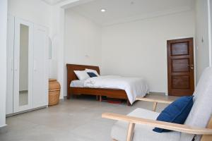 a white bedroom with a bed and a chair at Lokko Serene in Accra