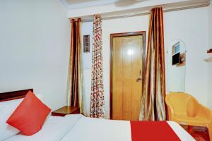 a bedroom with a bed with a red pillow and a door at Ratiram Hotel Near Worlds of Wonder in Kalkaji Devi