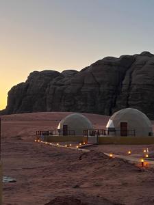 two domes in the desert with a mountain in the background at Orbit camp in Wadi Rum