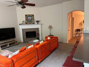 ein Wohnzimmer mit einem orangenen Sofa und einem TV in der Unterkunft Spacious Luxury 3BD Oasis Home North Richland Hills Texas in North Richland Hills