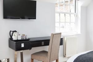 a black desk with a chair and a television on a wall at Chequers Inn by Greene King Inns in Maresfield