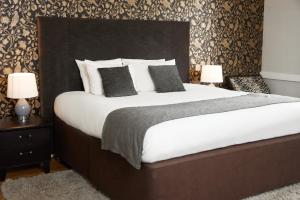 una camera da letto con un grande letto con lenzuola e cuscini bianchi di Chequers Inn by Greene King Inns a Maresfield