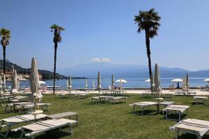 a group of tables and chairs with palm trees and the beach at Villa Prince Garda in Salò