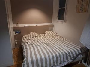 een klein bed in een slaapkamer met een gestreepte sprei bij House with outbuilding near Stade de France in Épinay-sur-Seine
